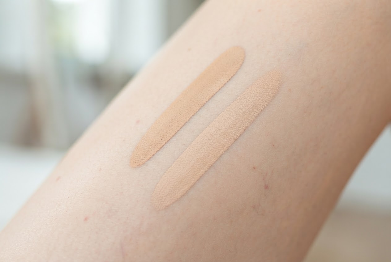 Close-up of a woman's thigh with two small streaks of leg make-up in different shades being tested; they blend naturally into the skin.