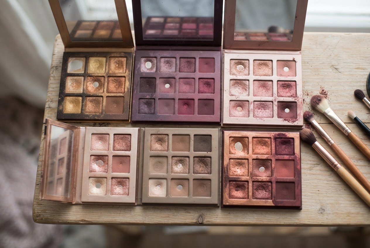 A flat lay of eyeshadow palettes with warm golds, bronzes, plums, rose golds, and earthy tones.