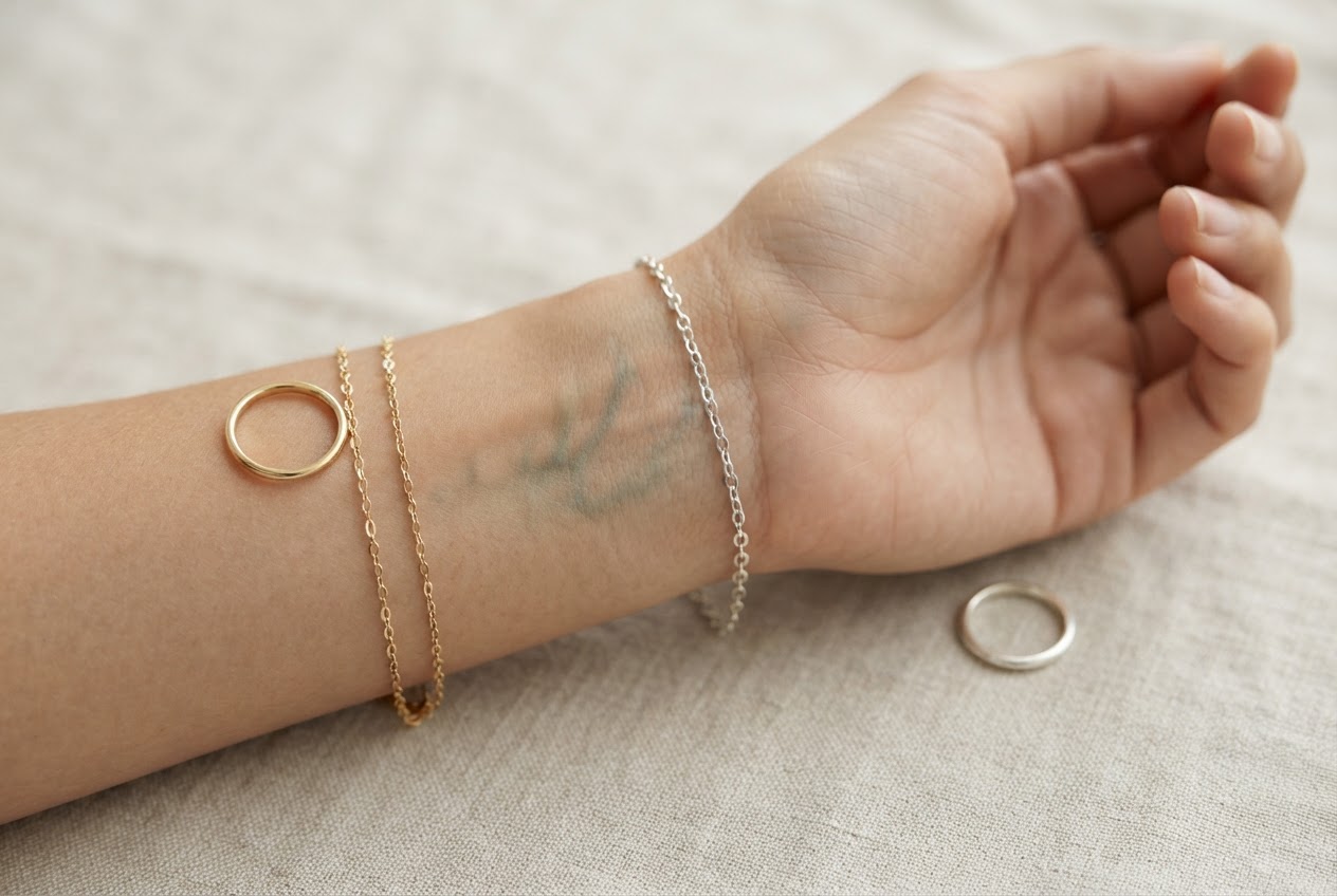 Close-up of a wrist showing veins, with gold and silver rings nearby to compare undertone.
