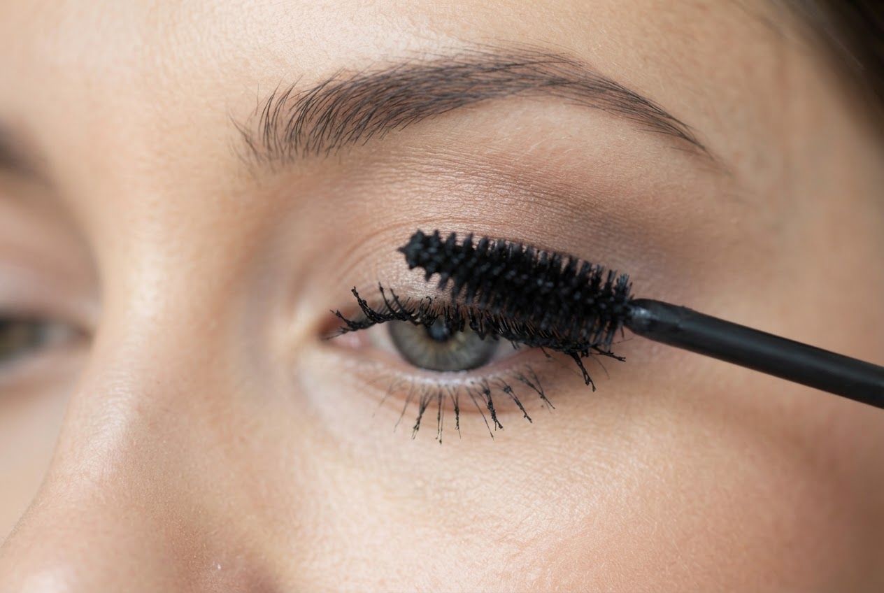 Close-up of an eye with mascara wand applying product in a zigzag movement from the lash base to tips.