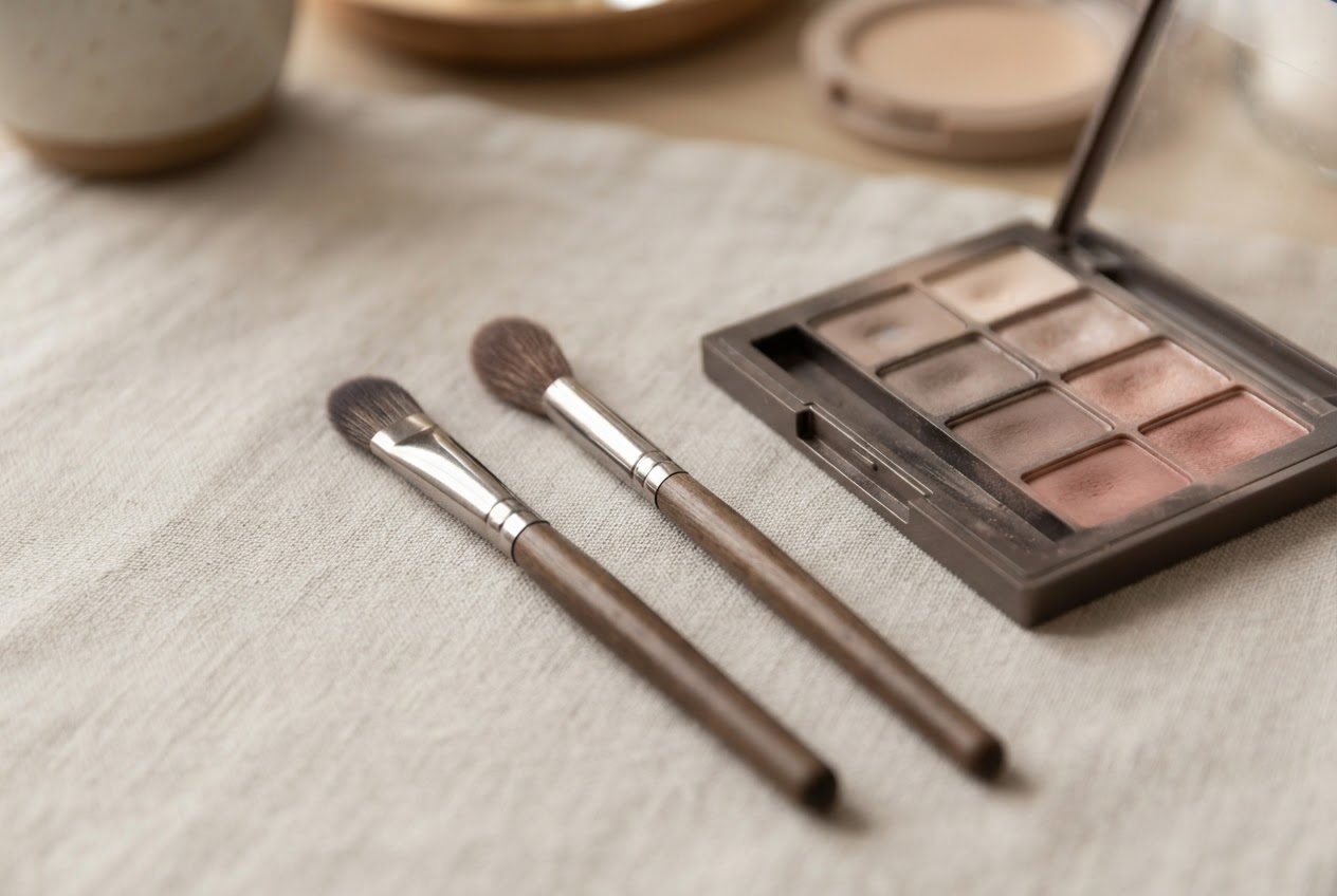 A flat brush and a blending brush next to an eyeshadow palette