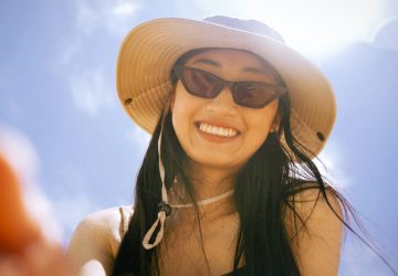 woman in black tank top wearing brown sun hat and black sunglasses